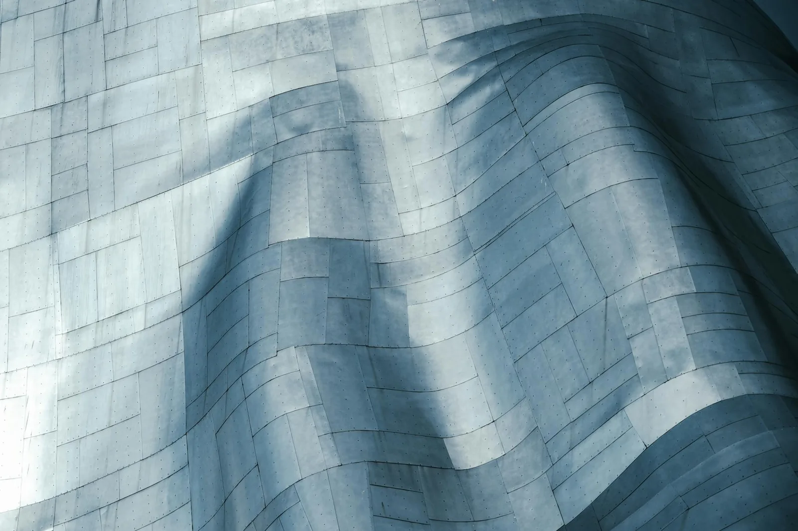 Building a Identify Program With a Team of 5 — Close-up view of a wavy metallic surface showcasing modern architectural desig…